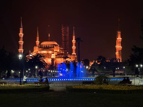       Illuminated mosque with large minarets at night.
  