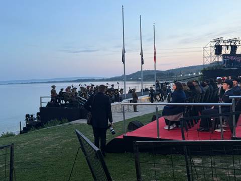 Audience watching a performance near a waterfront.