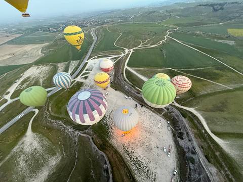       Hot air balloons flying over green fields.
  