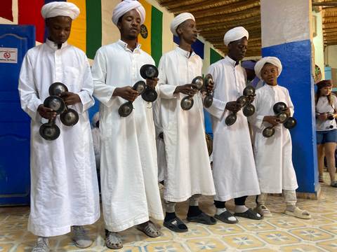 A group of performers in white robes with musical instruments.