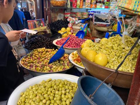 A market stall displaying various olives and lemons in bowls.