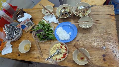       A table with various Vietnamese dishes, bowls, and chopsticks.
  