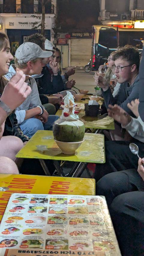      A group of people enjoying a dessert served in a coconut shell.
  