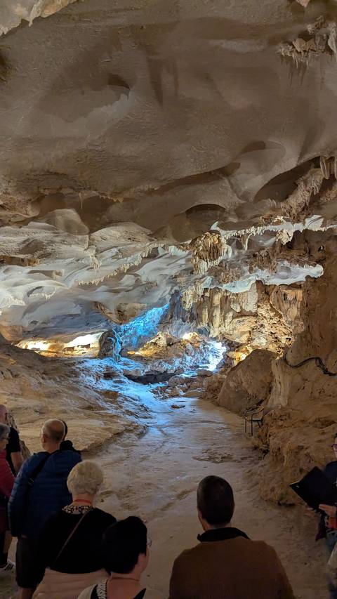       A cave interior with illuminated stalactites and stalagmites.
  