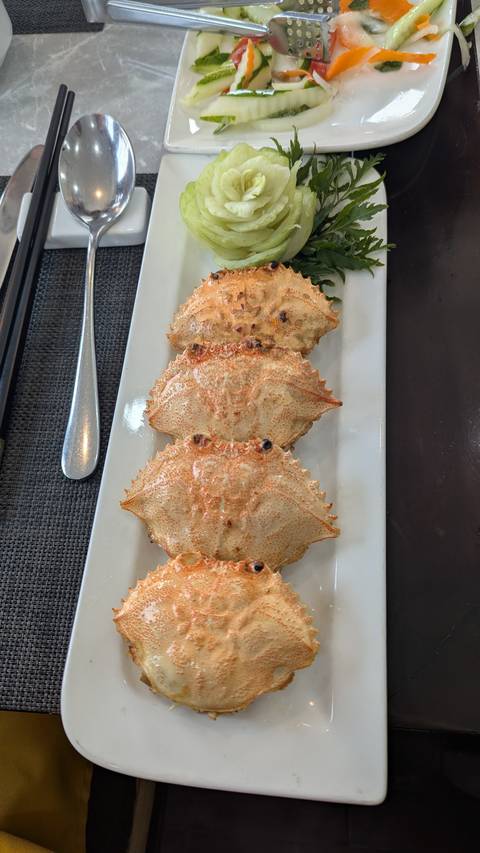       A dish featuring cooked crabs aligned on a white plate.
  