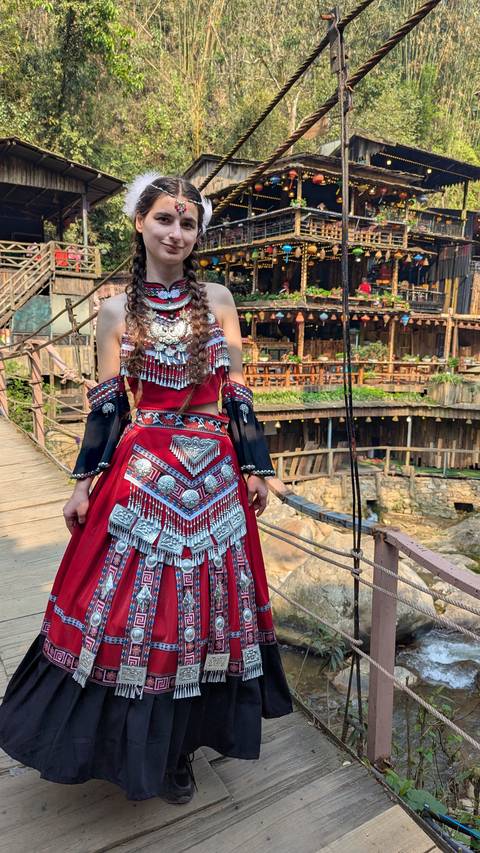       A person in traditional attire standing on a bridge.
  