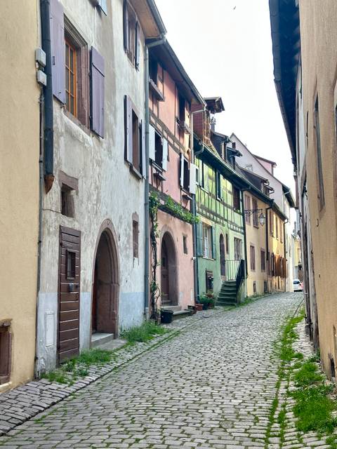 A narrow cobblestone street with pastel-colored buildings.