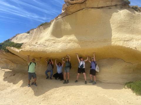 Group of people posing under a rock formation
