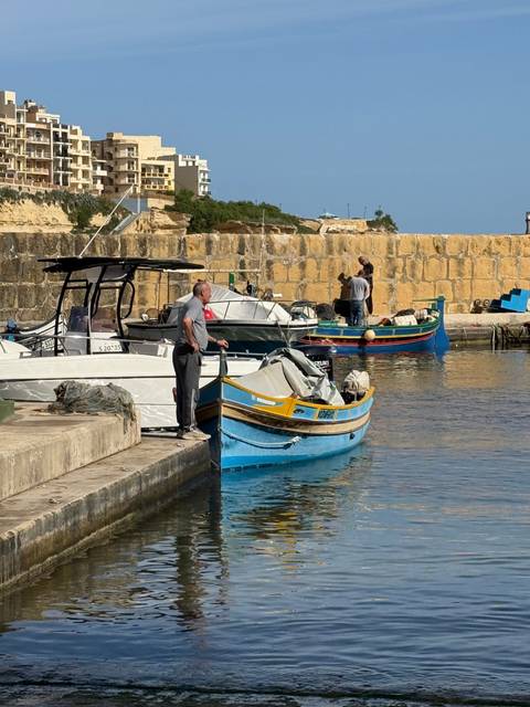 Man standing by boats docked at a harbor.