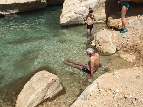 People enjoying a dip in clear, rocky waters.