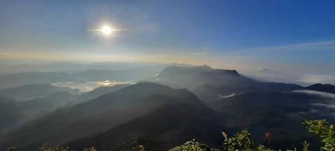 Sun shining over a mountainous landscape.