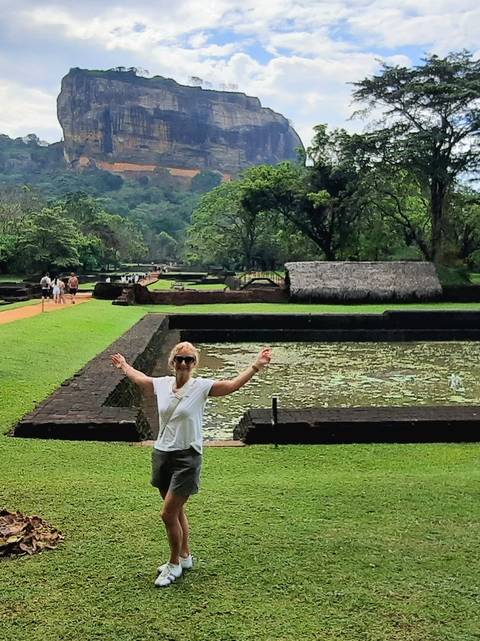       Woman posing in a lush garden with ponds.
  