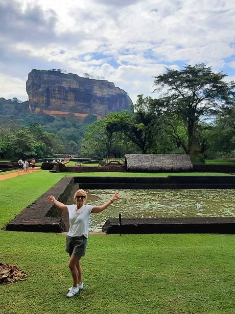 A person posing with the Lion Rock in the background.