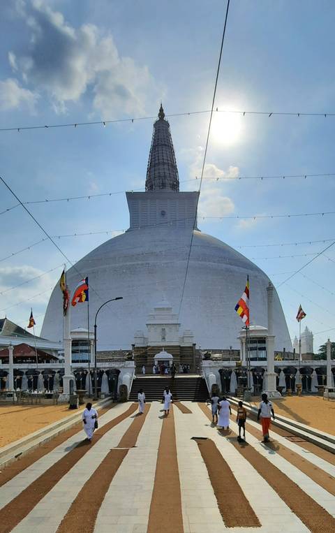       A stupa with flags in a Sri Lankan landscape.
  