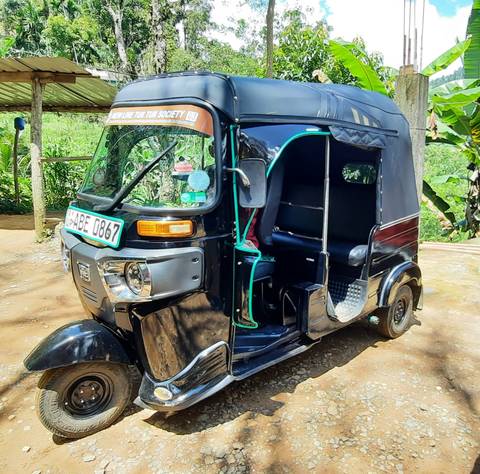 A tuk-tuk parked in a rural area.