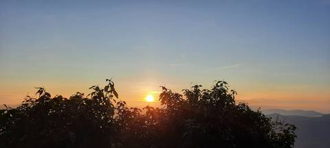       Sunrise over mountains and trees.
  