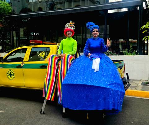 Two people in colorful costumes sitting on a vehicle.