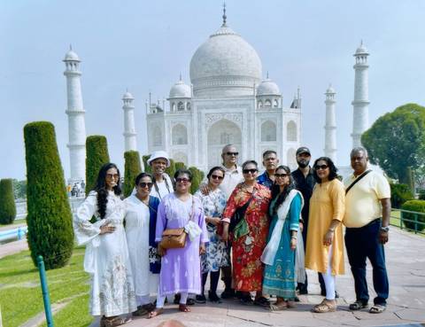 Group of people posing in front of the iconic Taj Mahal.