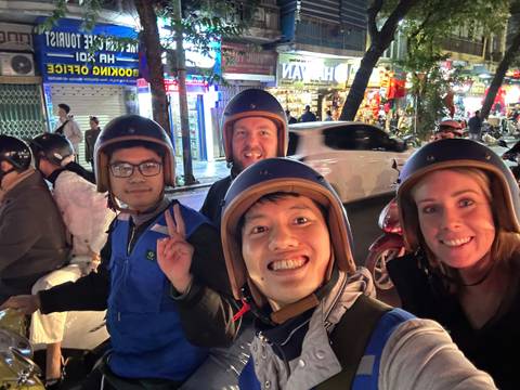 Group of people wearing helmets and smiling on a busy street.