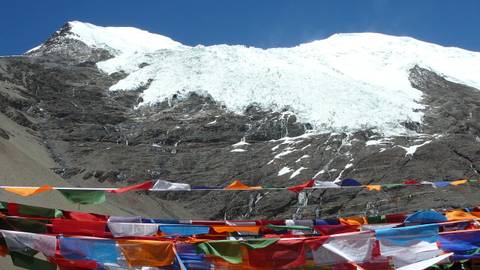 Glacier on a mountain with colorful prayer flags in foreground.