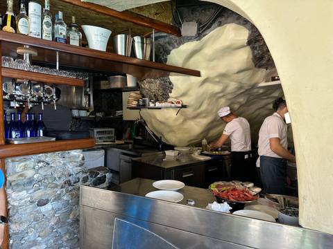 People working in a small restaurant with stone walls.
