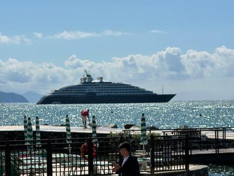       A large yacht on the sea with people on the shore.
  