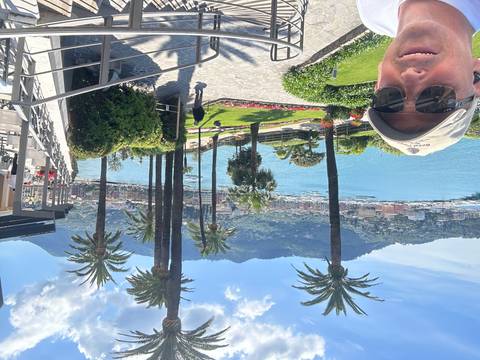 A man in sunglasses against a waterfront view.