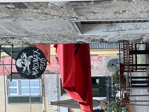 A street view with a pub sign and outdoor seating.