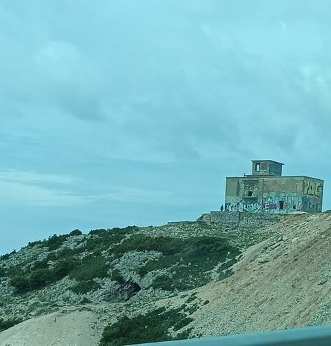 Abandoned graffiti-covered building on a hill.