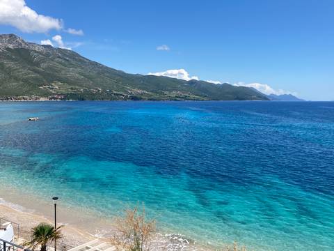       Coastal view with clear blue water and green hills.
  