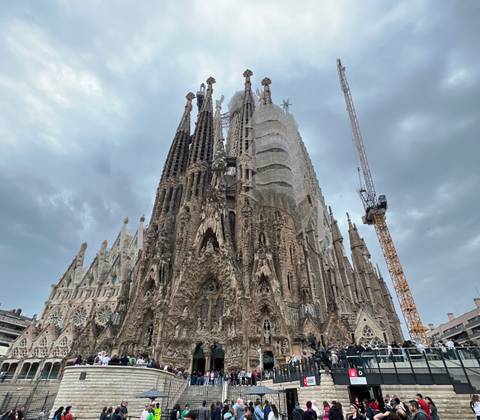       Sagrada Familia with scaffolding under a cloudy sky.
  