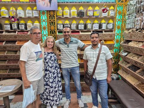 Group of people posing in a spice shop with shelving in the background.