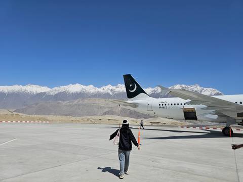 Person walking towards a parked airplane with mountains in the background.
