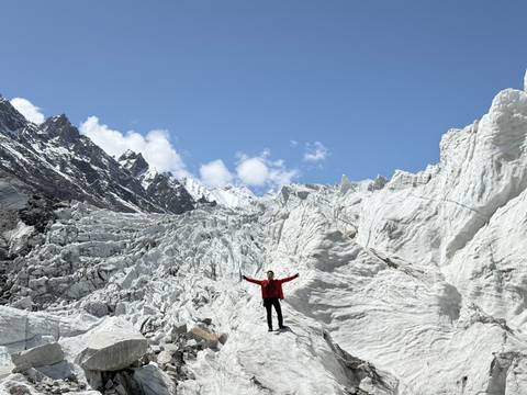       Person with arms raised on a snow-covered glacier.
  
