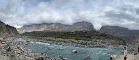 Vast landscape with a flowing river and cloudy mountains.