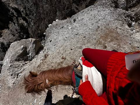       Person riding a horse along a mountainous trail.
  