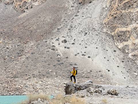 Person standing on rocky terrain with a vast mountain scenery.