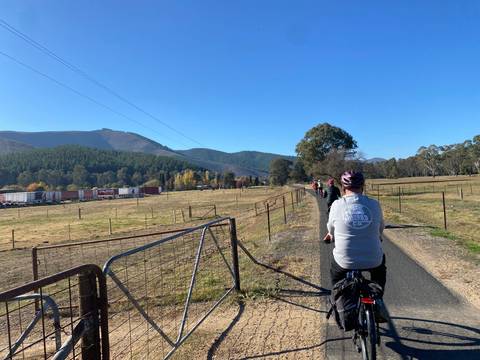 Cyclists on a rural path with mountains in the background.