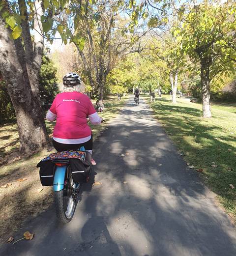 Person cycling on a scenic path with others ahead.
