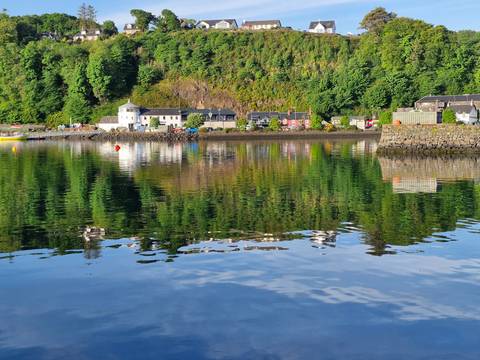       A picturesque village by a calm sea with reflections.
  