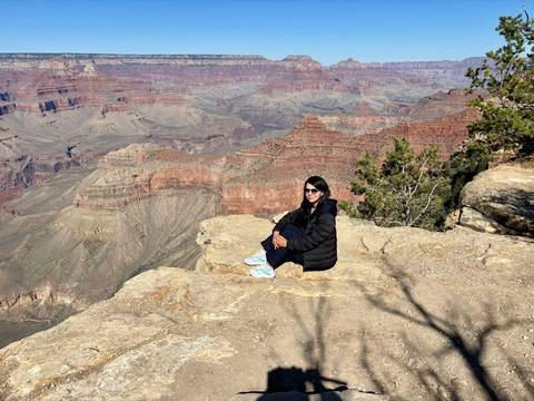 A person sitting on the edge of the Grand Canyon enjoying the view.