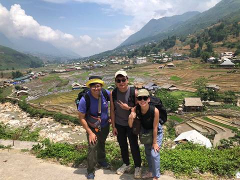 Trekkers standing with a scenic view of terraced fields.