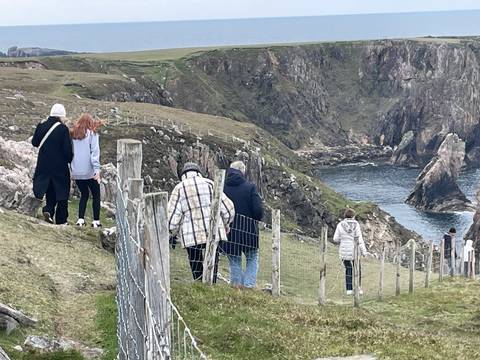 People walking along a rocky coastal path.