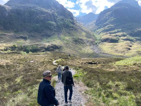 Hikers walking through a valley surrounded by mountains.