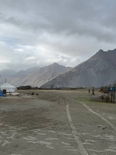       Camping area with tents near majestic mountains.
  