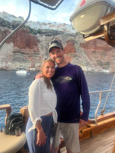 Couple posing in front of a rocky coastline.