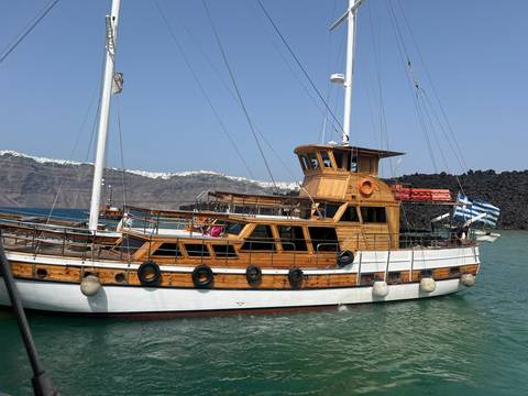 Wooden sailboat docked near a rocky shore.