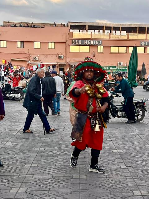 Street performer in colorful traditional attire with bells.