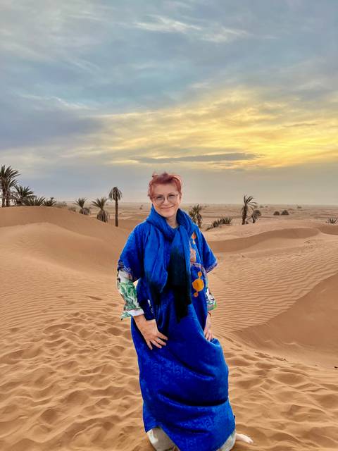 Person in bright clothing standing in a desert at sunset.