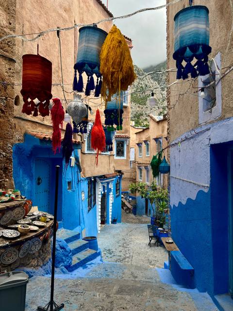 Blue-walled street lined with colorful hanging decor.